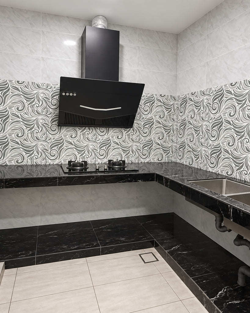 A kitchen finished in black marble-effect tile with a patterned tile splashback, a black cooker hood and a twin stainless sink.