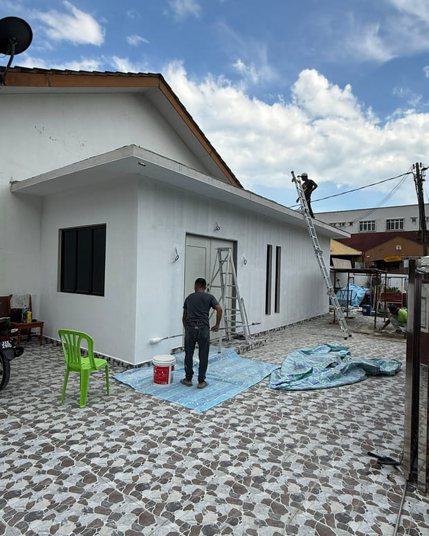 A new flat-roofed white extension block with door and window openings formed, seen across a large patterned-paver forecourt.