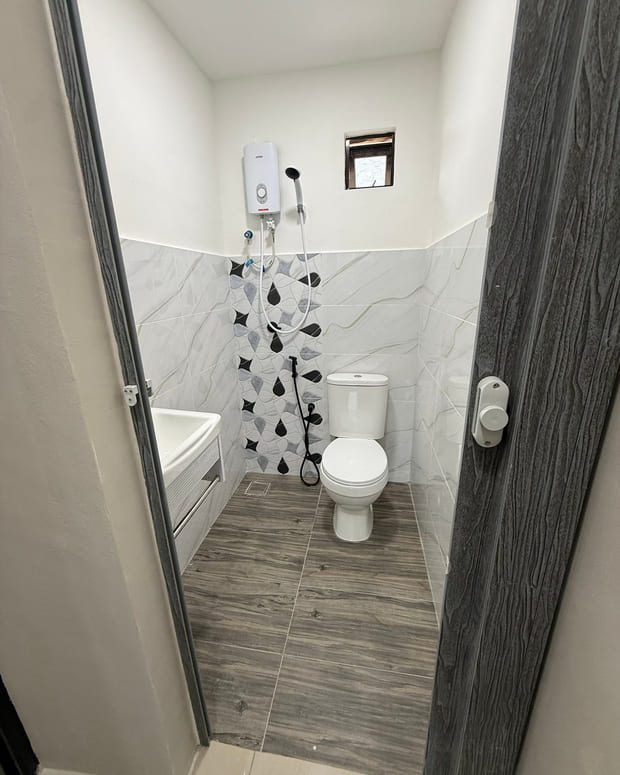 A compact bathroom with half-height white marble-effect wall tile, a black-and-white leaf-pattern feature strip, a close-coupled WC and dark wood-effect plank floor tile.